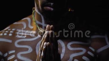 戴着白色仪式图案和项链的平安巴布亚人在黑暗中缓慢地祈祷
